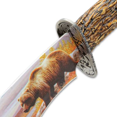 Close-up of knife blade with bear illustration and ornate guard