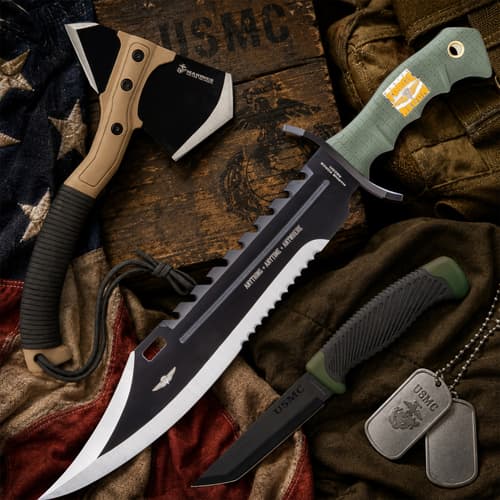 USMC-themed knives and axe on wooden background