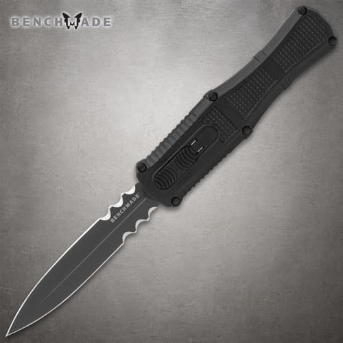 Black serrated knife with textured handle on gray background