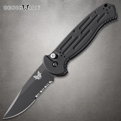 Black folding knife with serrated blade on gray background