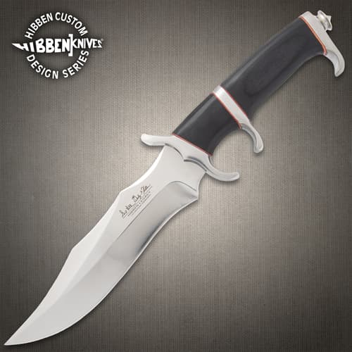Legacy III fighter knife with black, silver, and red accents on a background of black rocks.