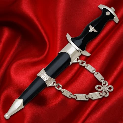 Black-handled dagger with silver details and chain on red fabric