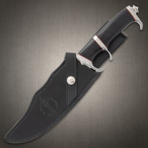 Large knife with black, red, and silver, hilt exposed with the blade enclosed in a black leather sheath stamped with "Hibben Knives" logo