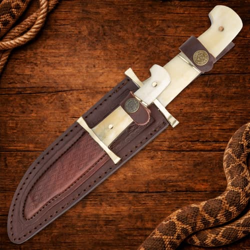 Knife in leather sheath on wooden surface