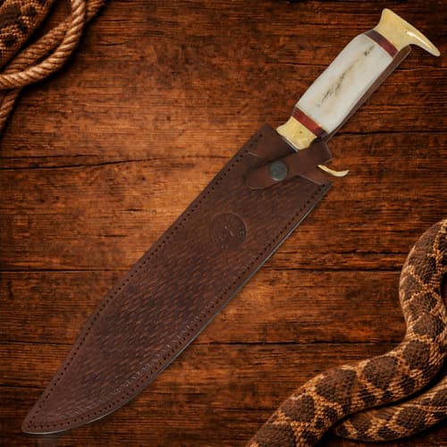 Knife in a brown leather sheath on wooden surface