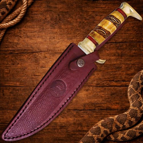 Bowie knife in a leather sheath on wooden background