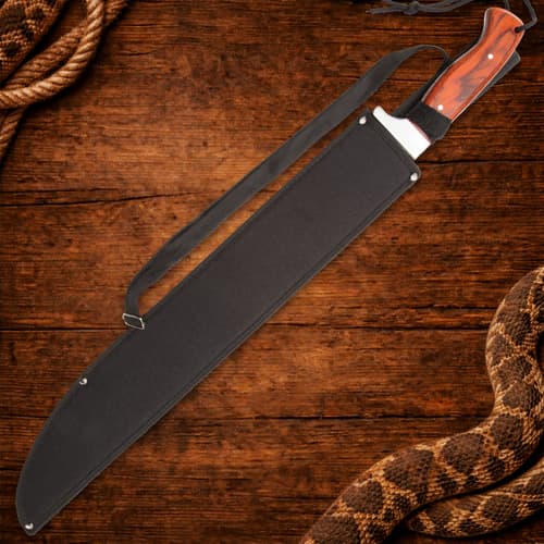 Machete in black sheath with wooden handle on wood surface