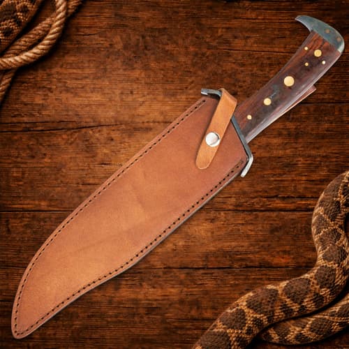 Knife in leather sheath on wooden background with rope