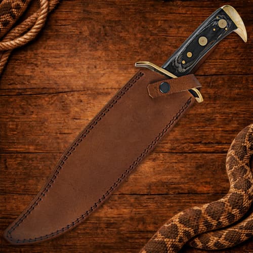 Knife in brown leather sheath on wooden background with rope