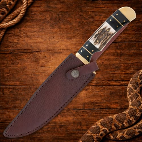 Knife in leather sheath on wooden surface with rope