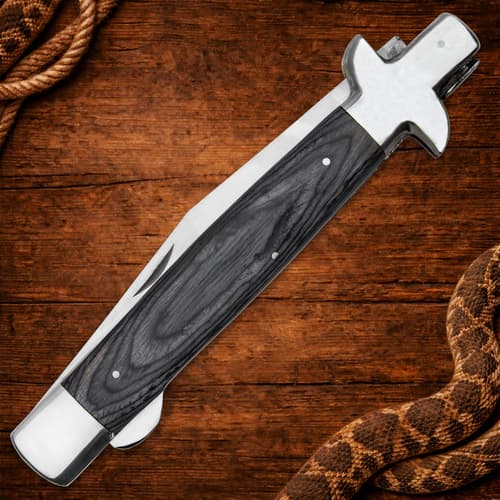 Closed Timber Rattler knife with wooden handle on wood background