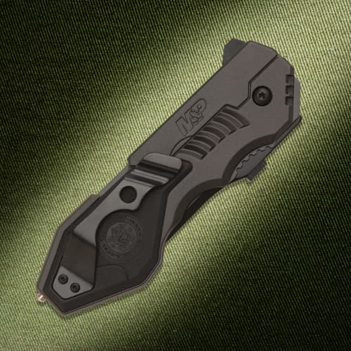 Closed black tactical knife with clip on textured background