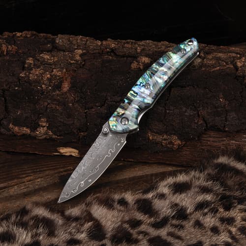 Pocket knife with abalone handle on a wooden background