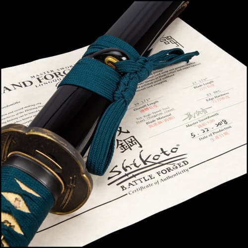 Katana with tsuka wrapped in a teal cord and tea dyed rayskin encased in black scabbard with a teal cord around a brass knob