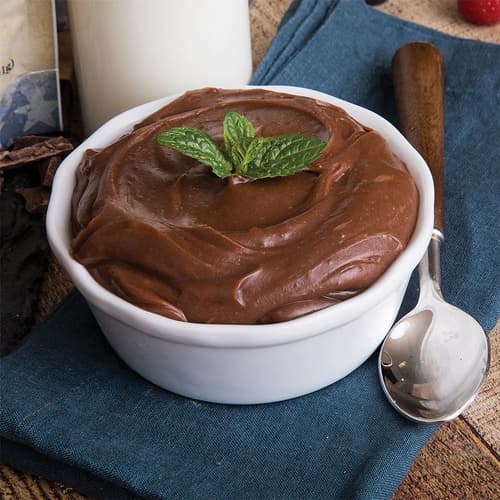 A prepared pudding from the Emergency Essentials Food Kit shown served in white bowl with silver spoon.