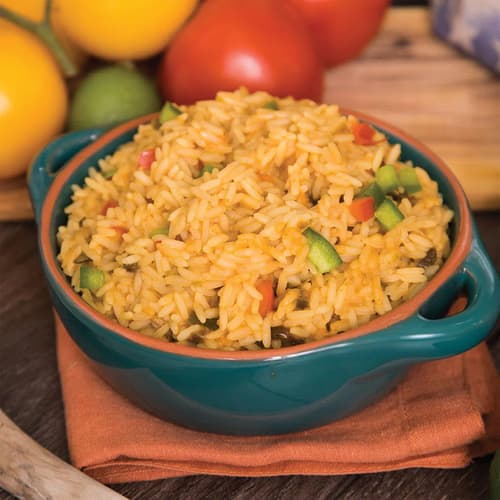 Rice, prepared from the Emergency Essentials Emergency Food Kit, shown in a blue bowl with vegetables in the background.