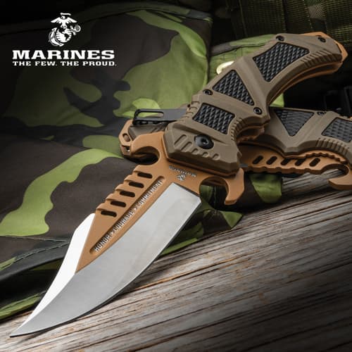 USMC pocket knife on camo fabric with wooden background