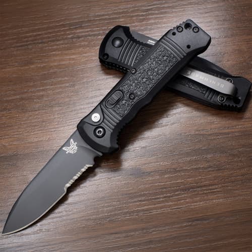 Two black folding knives, one open, on a wooden surface