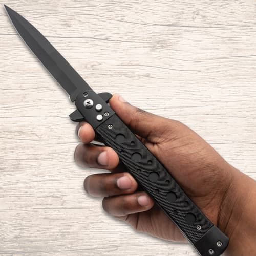 Hand holding a black stiletto knife