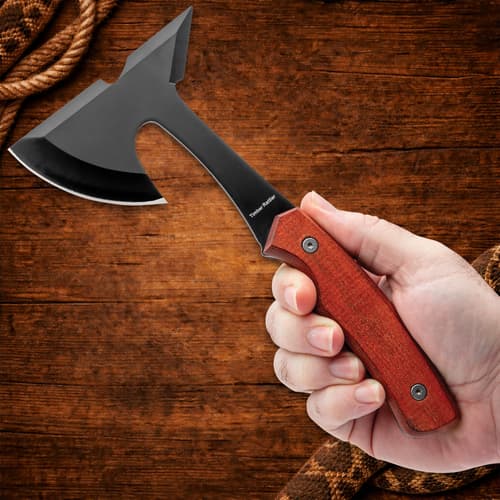 Hand holding a black axe with wooden handle
