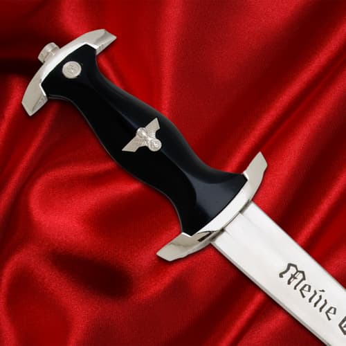 Close-up of dagger handle with silver emblem on red fabric
