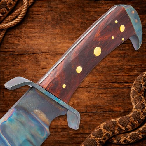Close-up of knife handle with brass accents on wooden background