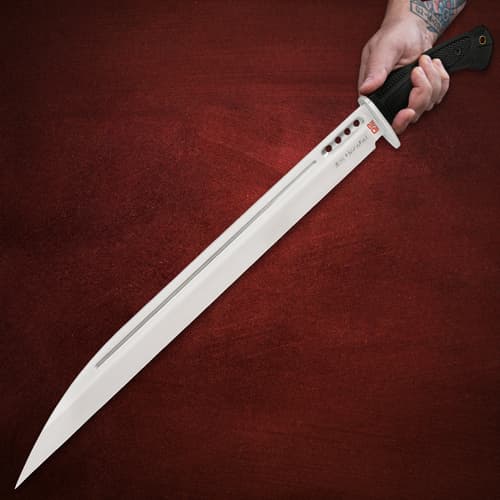 Hand holding Honshu D2 knife with black handle on red background