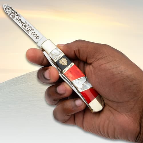 Hand holding a decorative pocket knife with engravings