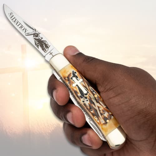 Hand holding a pocket knife with cross design