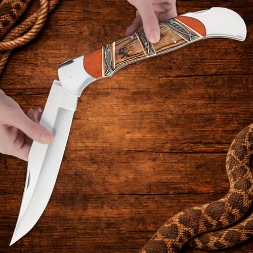 Hands holding open folding knife on wooden background