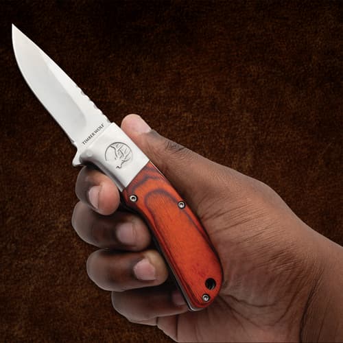 Hand holding Timber Wolf pocket knife with wood handle