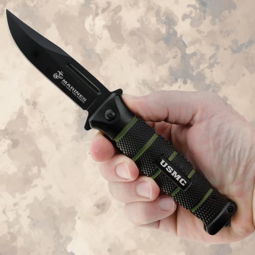 Hand holding USMC combat knife with black blade