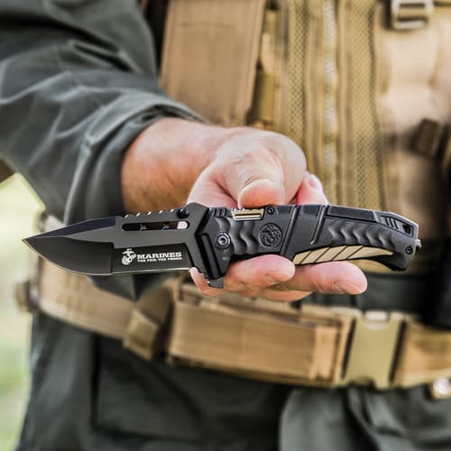 Person holding a black tactical knife with USMC logo