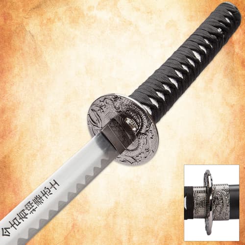 Close-up of katana handle and engraved guard on textured background