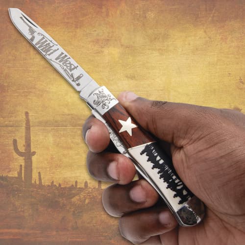 Hand holding a knife with Wild West engravings