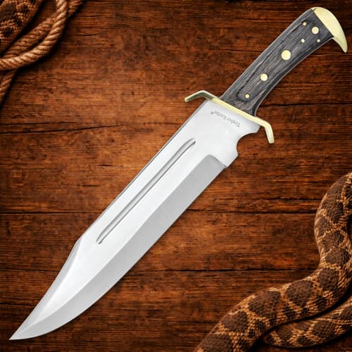Full view of bowie knife with wooden handle on wooden surface