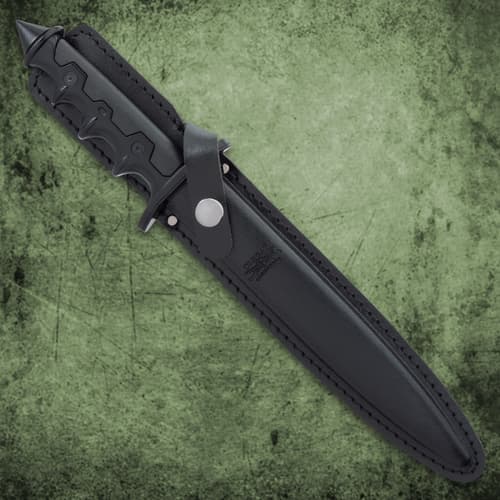The 8 1/8” 1065 carbon steel blade is shown stabbed into a wooden table with background of tactical gear.