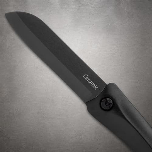 Close-up of the black pocket knife blade marked Ceramic, with its cutting edge, pivot screw and part of the handle visible