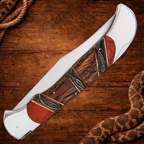 Closed folding knife with decorative handle on wooden surface