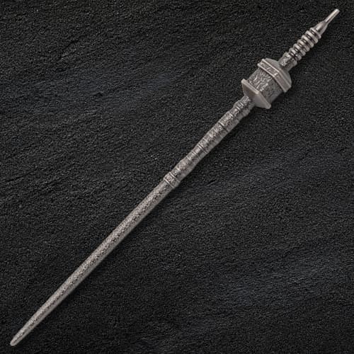 Intricately designed metal needle on a dark textured surface