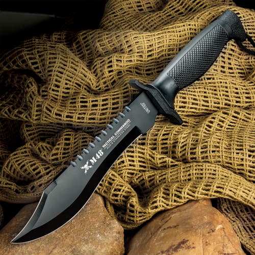 Black tactical knife on textured fabric and rocks