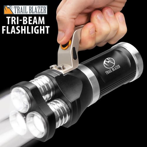 Hand holding a tri-beam flashlight with three bright beams