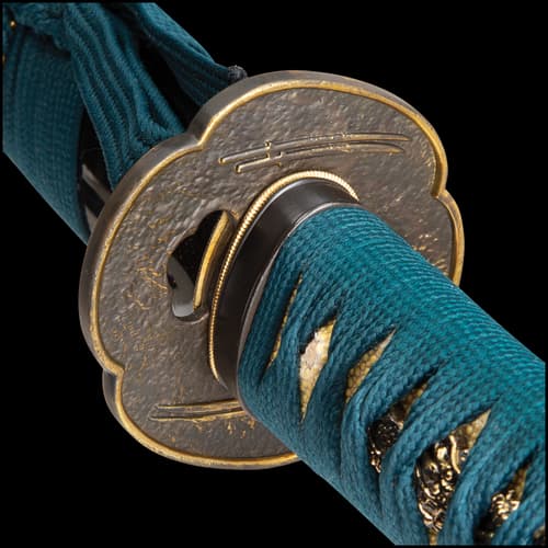 Katana sword with brass tsuba and handle with teal cord rayskin on top of a black scabbard displayed on a black wooden stand