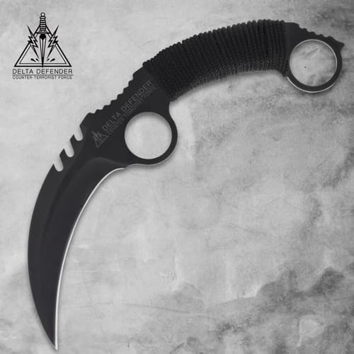 Black karambit knife with cord-wrapped handle on gray background
