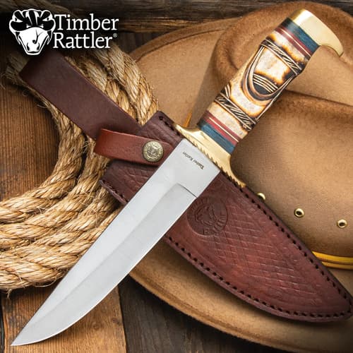 Bowie knife with leather sheath on cowboy hat and rope
