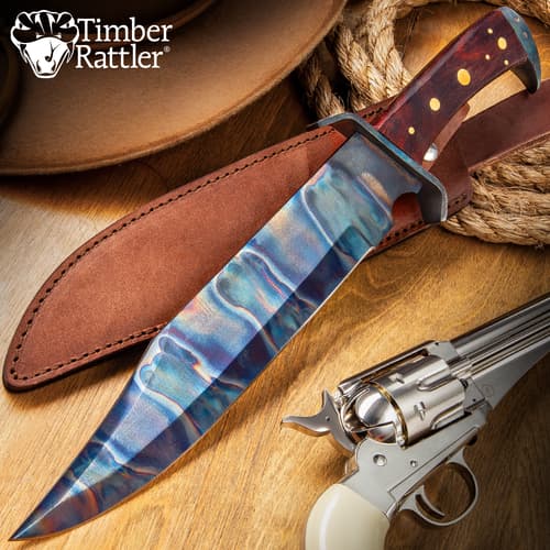 Colorful knife with leather sheath and revolver on wooden surface