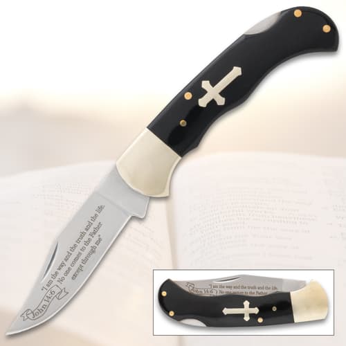 Folding knife with cross inlay and engraved blade on open book