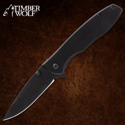 Black folding knife with Timber Wolf logo on brown background