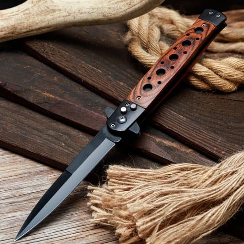 Stiletto knife with wooden handle on rustic wood and rope