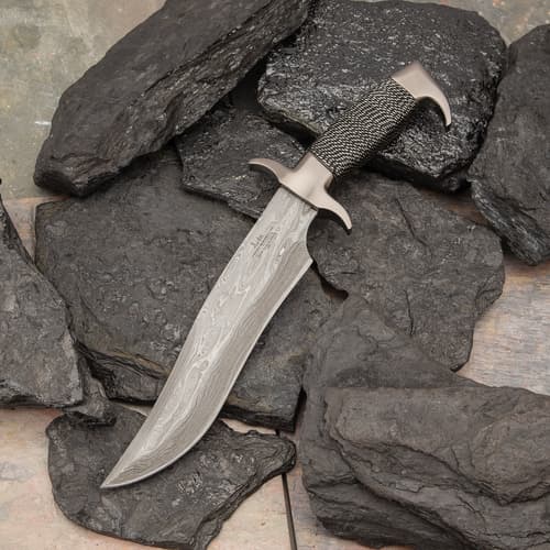 Knife with Damascus blade on dark rocks